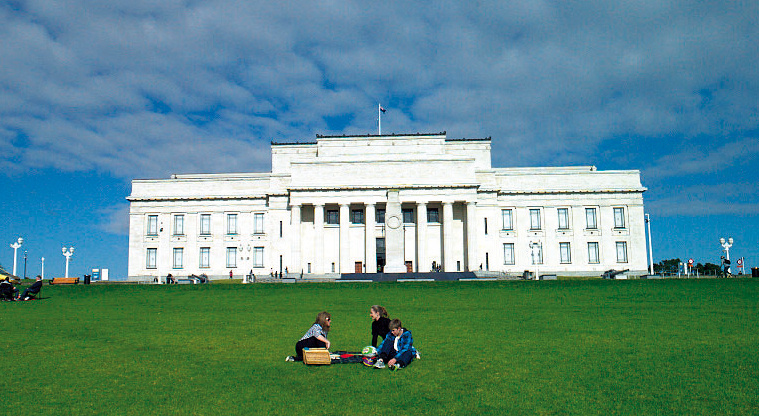 Auckland War Memorial Museum, a large white building, on an expanse of grass with picnickers