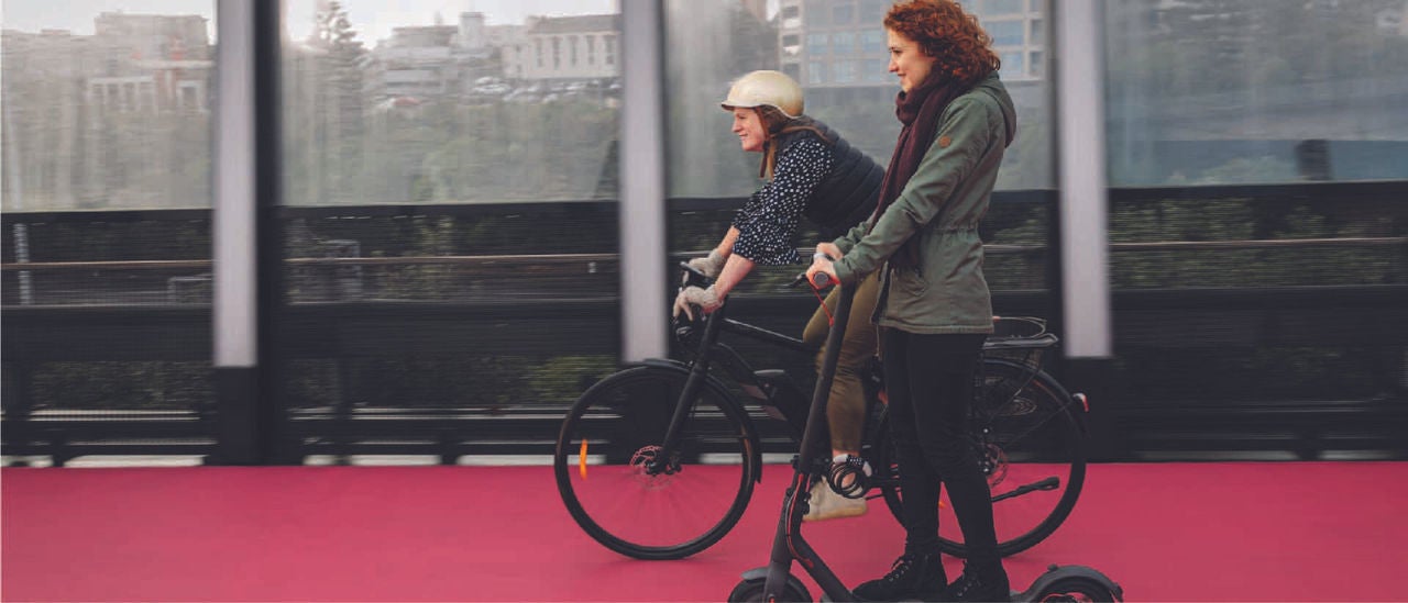 People riding electric biycles and electric scooters on Auckland lightpath.