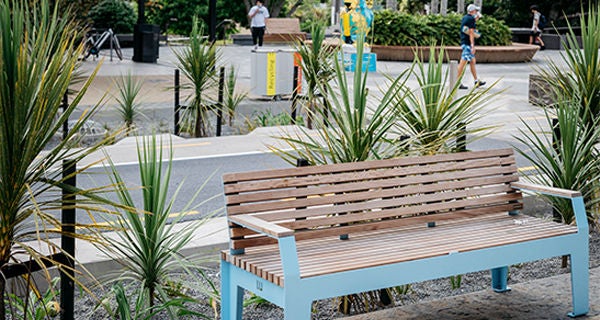 A wooden bench with blue legs installed as part of the Hurstmere Road transformation.