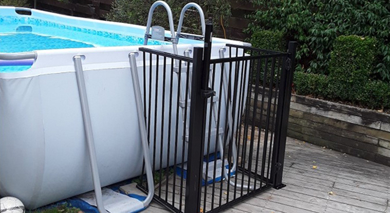 Fence around a ladder climbing up into an above-ground pool.