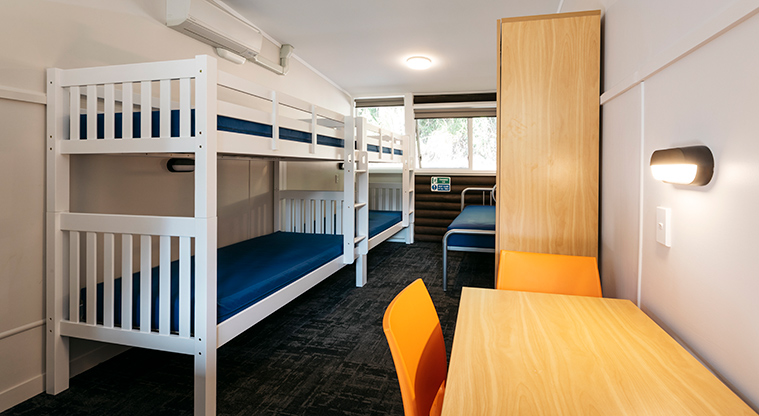 Huia Lodge - Inside one of the bedrooms showing two double bunk beds, a single bed and a desk.