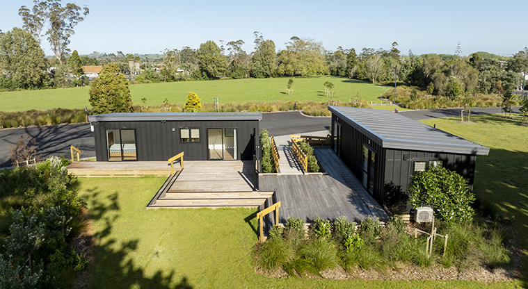 Te Kopua tiny home - Back view of Te Kopua and Te Tino tiny homes surrounded by open space and trees.