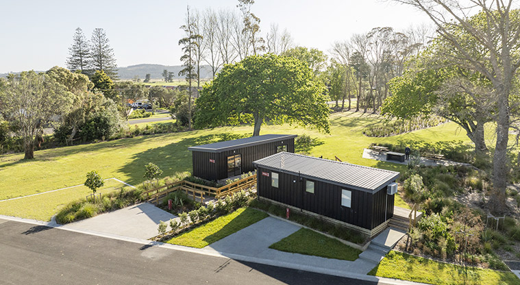 Te Kopua tiny home - Front view of Te Kopua and Te Tino tiny homes surrounded by open space and trees.