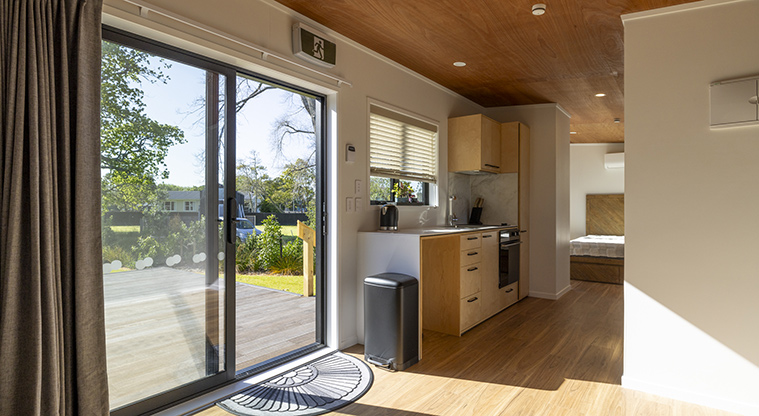 Te Kopua tiny home - Looking out to the deck with the kitchen and bedroom in the background.