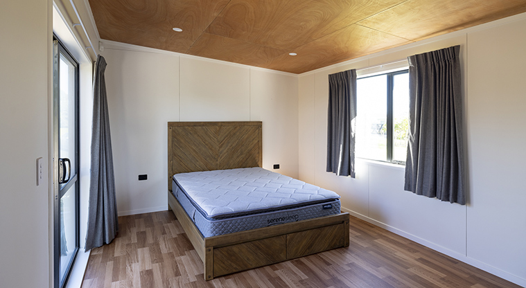 Te Tino tiny home - Bedroom with a window with curtains.