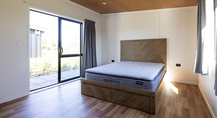 Te Tino tiny home -  The bedroom and section of the deck with the Te Kopua tiny home in the background.