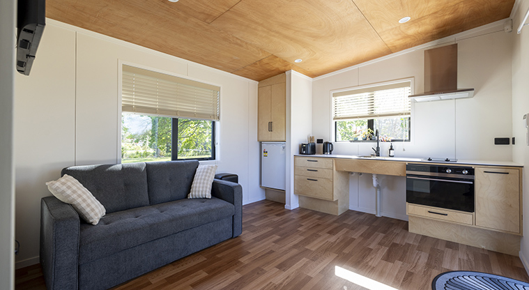 Te Tino tiny home - Lounge area with a fold-out couch and the kitchen.