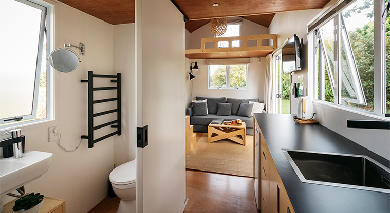 Mahana tiny home - Kitchen and bathroom with the living area in the background.