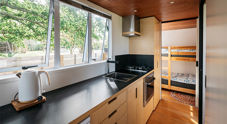 Mahana tiny home - Kitchen area with the bunk bedroom in the background.