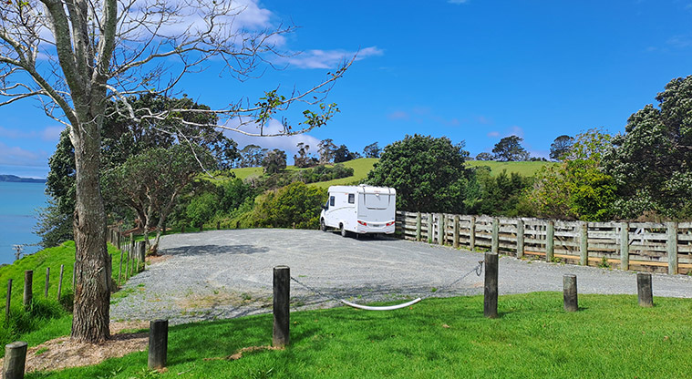 Scandrett CSC parking area - Motorhome parked on the gravel with a fence and trees in the background.