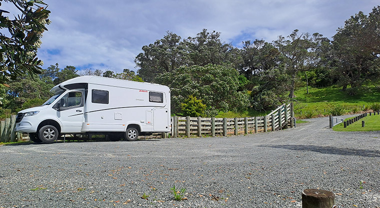 Scandrett CSC parking area - Motorhome parked on the gravel with a wooden fence on the right, and trees and view in the background.