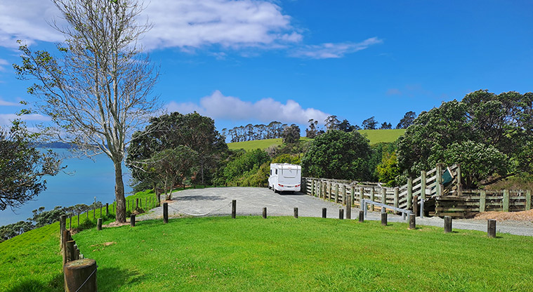 Scandrett CSC parking area - Motorhome parked on the gravel with a wooden fence on the right, and trees and view in the background.