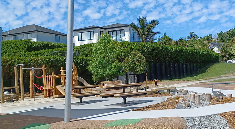 86 Harvest Avenue - Picnic tables on a flat concrete surface between the nature area and low climbing structure.