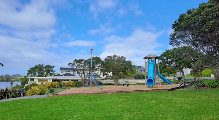 Algies Bay Reserve – Grassy area with a playground in the background. Photo credit: M Woodside.