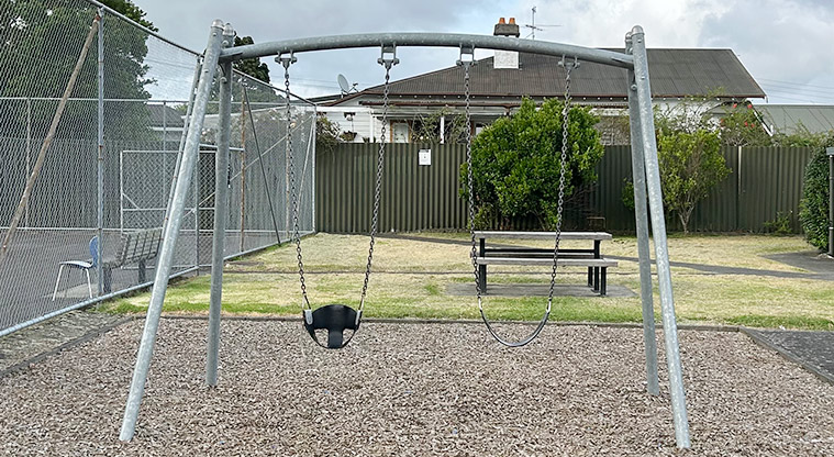 Anderson Park - Set of two swings with a picnic table in the background. Photo credit: S Hulse.