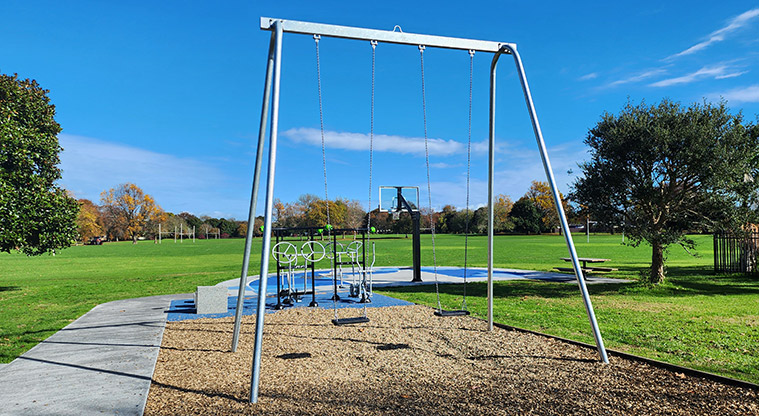 Aorere Park - A set of two high swings with the fitness equipment and sports fields in the background.