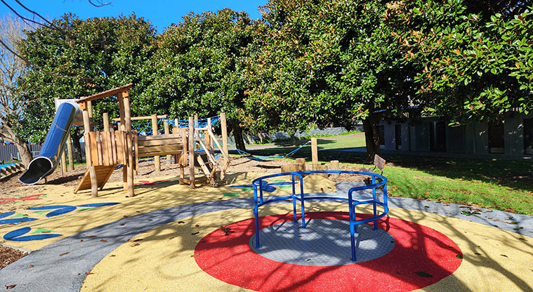 Aorere Park - Blue wheelchair accessible spinner with the rest of the playground in the background.