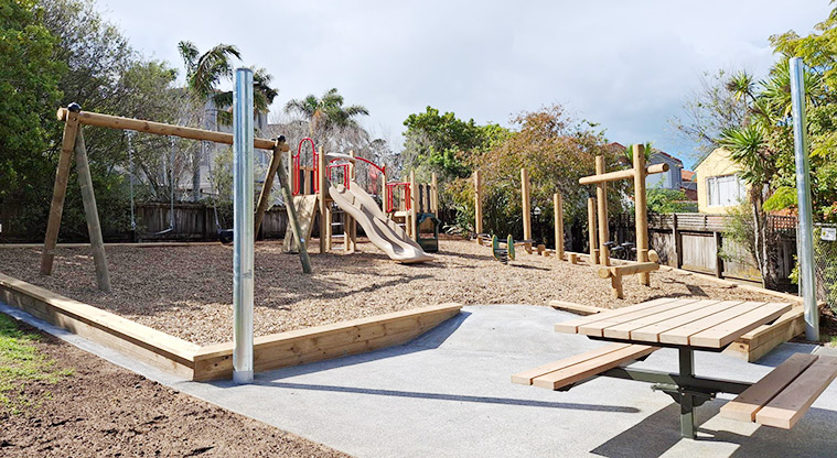 Belle Verde Reserve - Whole playground with swings, junior play module, climbing and balancing equipment for older kids, and a picnic table in the foreground.