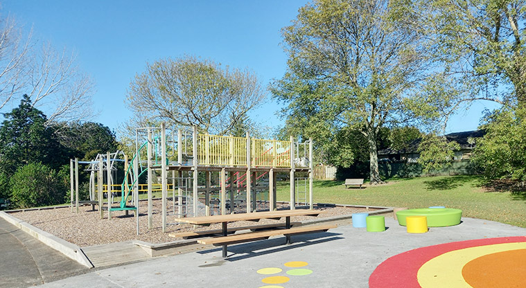 Onewherowhero / Brains Park - Playground with climbing and climbing and balancing equipment and swings, with a picnic table and colourful seating in the foreground.