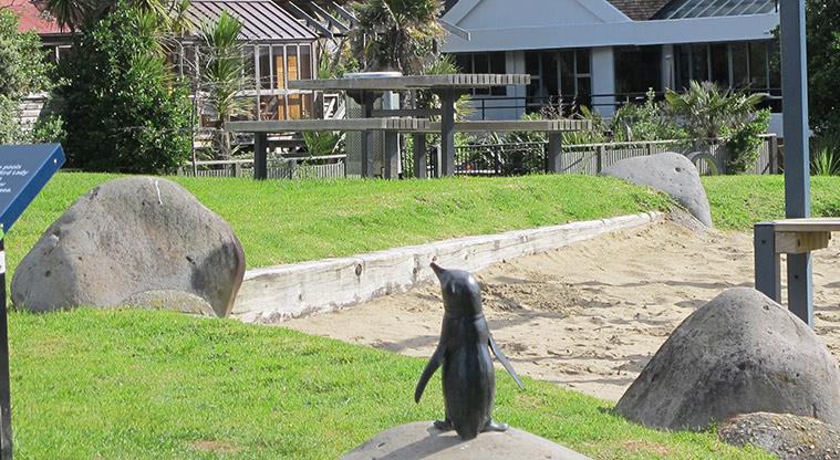 Campbells Bay Beach - One of the six bronze statues of little blue penguins / kororā overlooking the beach.