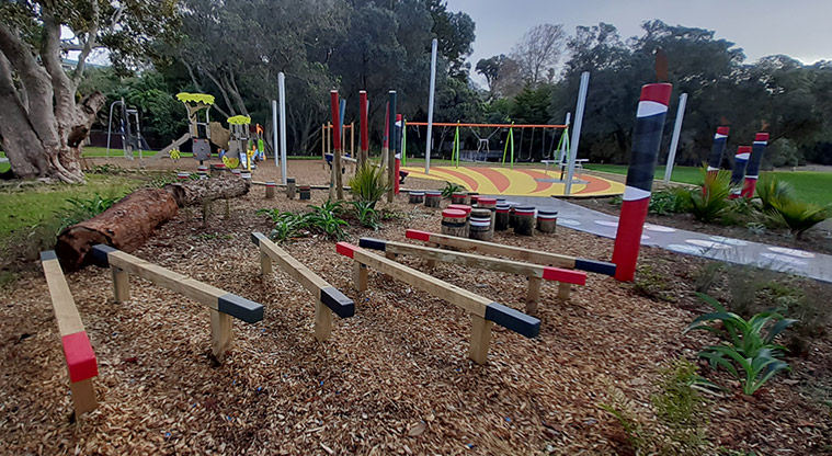 Cockle Bay Reserve - Section of the nature area in the playground with coloured balance beams and stumps, and the rest of the playground in the background.