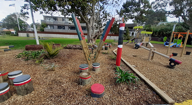 Cockle Bay Reserve - Colourful balance stumps, and poles, with the rest of the playground in the background.