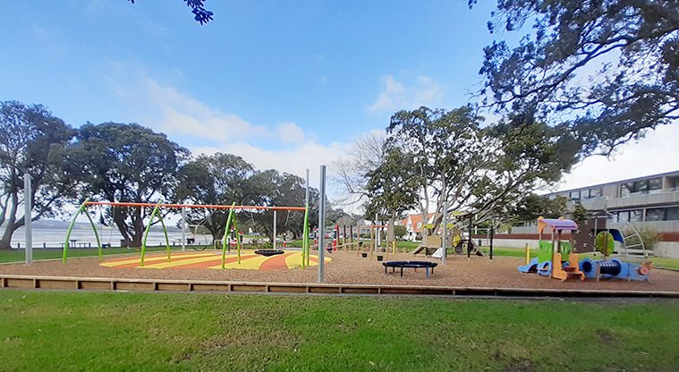 Cockle Bay Reserve - Whole playground with open grassed space, trees, and view over Cockle Bay.