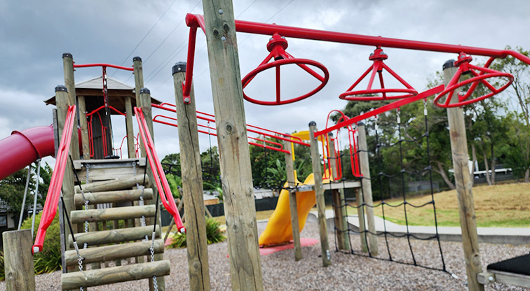 Toetoe-roa / Cooper Park - Part of the playground showing climbing and hanging equipment, wobbly log steps and slides.