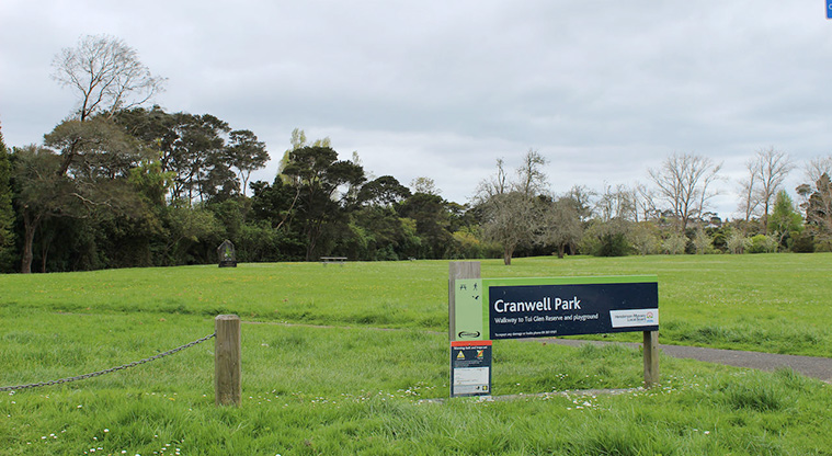 Cranwell Park - Sign at the entrance to the park with open space, trees and picnic tables in the background.