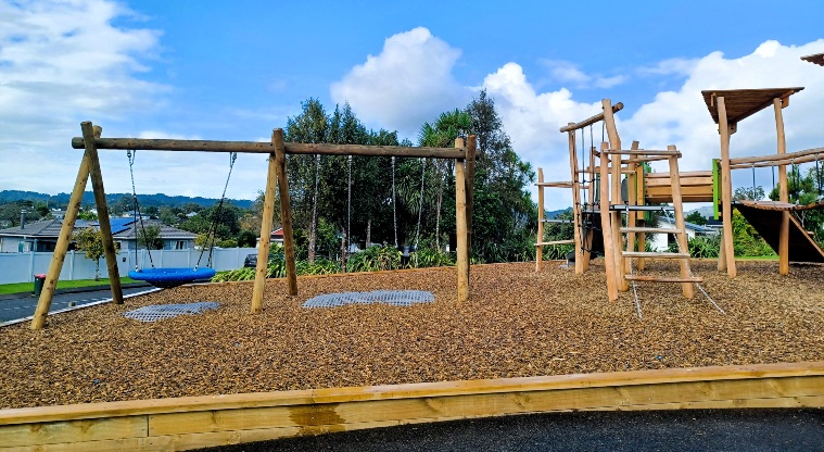 Dalmatia Green - Set of three swings including a basket swing, and part of the play module showing ladders, platforms and a crawl tunnel.