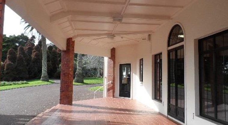 David Nathan Park - Section of the Nathan Homestead building and driveway, with large trees in the background.