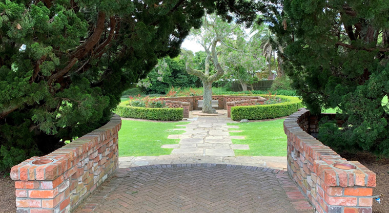 David Nathan Park -Looking through an archway of trees through to a circular garden with seating.