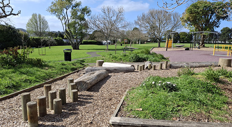 Eastdale Reserve - The playground with stepping logs and posts, swings, spinning roundabout and slide, with open space and trees in the background.