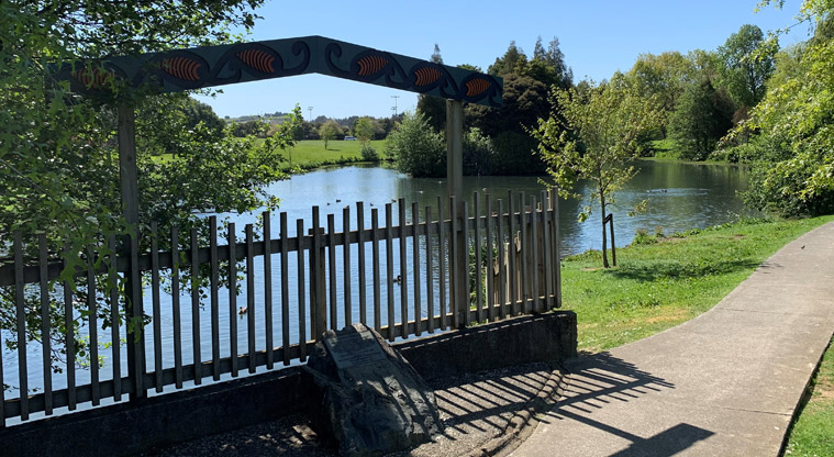 Ernies Reserve - Plaque on a rock with a section of fence and the pond in the background.
