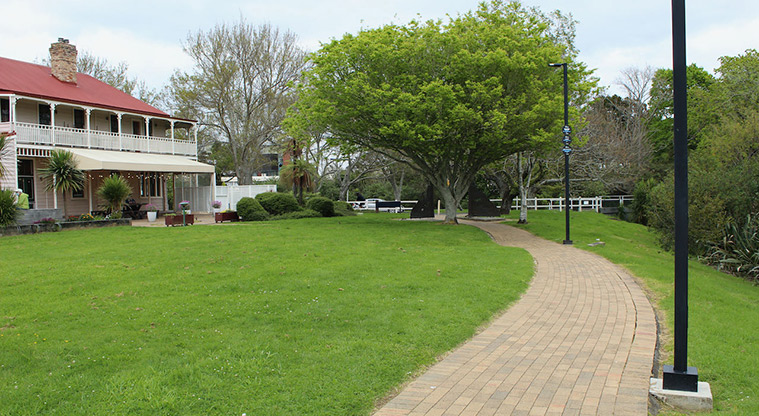 Falls Park - Path leading west with open grassed space, trees and the Falls Hotel in the background.