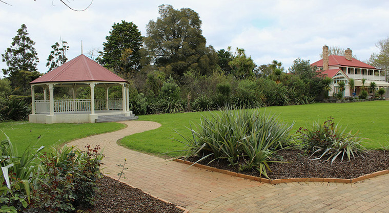 Falls Park - Section of brick path leading to the rotunda with open space, trees and the Falls Hotel in the background.