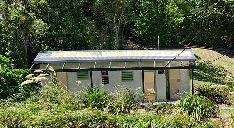 Tauihu / Green Bay Beach - Toilet block surrounded by trees and bushes. Photo credit: T Hodder.