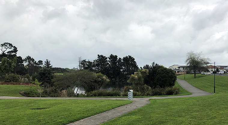 Harbourside Esplanade Reserve - Paths and rubbish bin, with trees and a pond in the background.