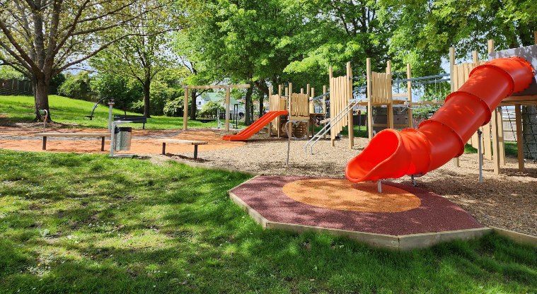 Pā o Tahi / Hillside South Park - Playground with slides, seating and trees.