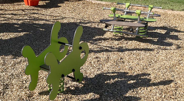 Howick Domain - Two green rocker toys on a bark base.