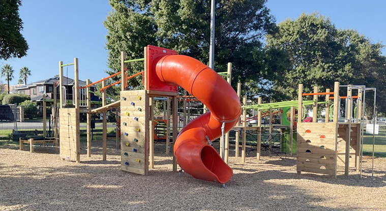 Howick Domain - Orange covered slide at the end of the play module for older kids, with the rest of the playground in the background.