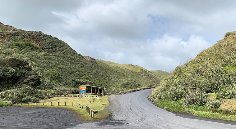 Karioitahi Reserve - Parking area with the toilet block and road in the background.