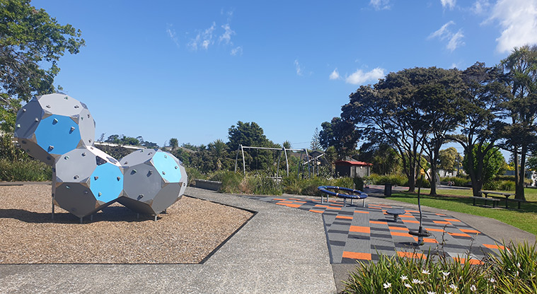 Kuaka Park - Climbing shapes, spinning toys, swings and trees in the background. Photo credit: J Grigg.