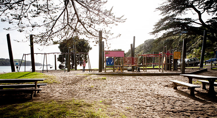 Little Oneroa Reserve - Playground with picnic tables in the foreground and the beach in the background. Photo credit: Jay Farnworth.