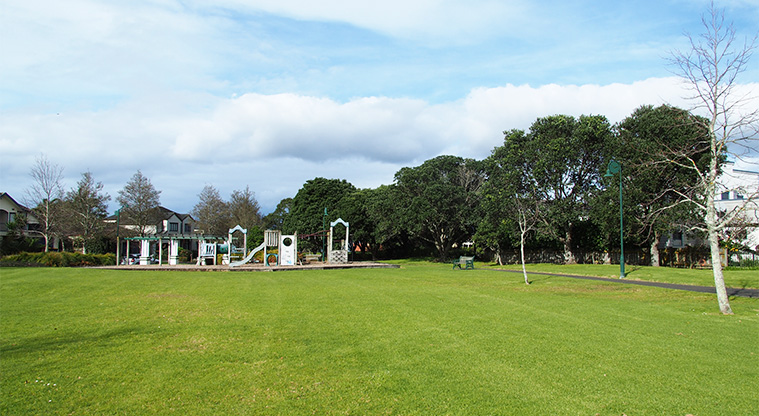 Lone Tree Park - Open grassed area with the playground and large trees in the background. Photo credit: Tracey Hodder.
