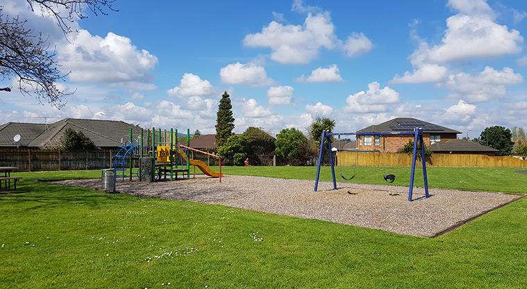 Longford Park Link Reserve - Small playground and swings with trees and houses in the background.
