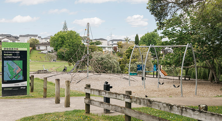 Wairaki / Lynfield Reserve - Sign at the entrance to the reserve with a wooden plank fence and the playground in the background. Photo credit: J Farnworth.