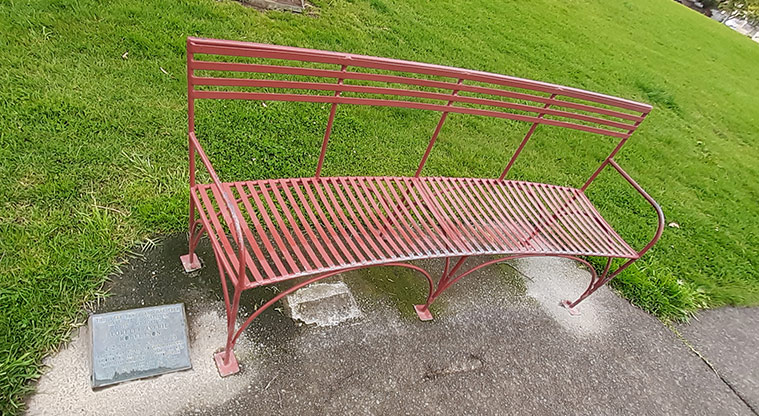 Madills Farm Recreation Reserve - Metal seat on the edge of the path with a small plaque set into the concrete.