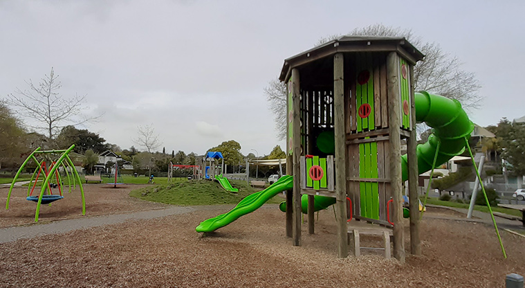 Madills Farm Recreation Reserve - High play tower with two slides and viewing windows, standalone basket swing, and the rest of the playground in the background.