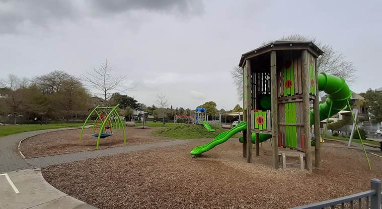 Madills Farm Recreation Reserve - High play tower with two slides and viewing windows, standalone basket swing, a path on the left, and the rest of the playground in the background.